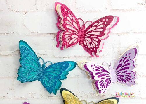 3d paper butterfly made with cardstock and a cutting machine. Butterflies are layered pink, teal and purple