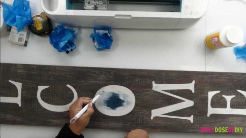 Pulling the stencil off of a vertical welcome sign using Cricut weeding tools