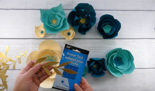 Use poster tack to hang greenery and small flowers to make a paper flower backdrop