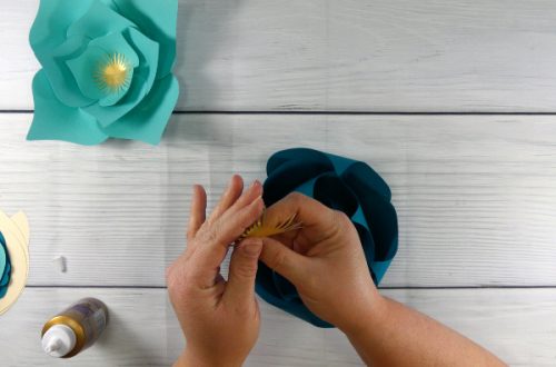 Curl up the stamen of the flower and glue it to the center of the teal paper flower