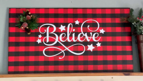Finished Christmas sign with a painted buffalo plaid base and a vinyl believe decal