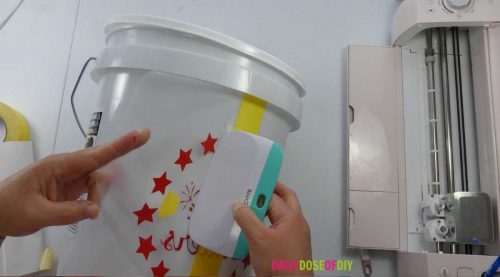 Apply the vinyl decal to your camp bucket with your Cricut scraper tool