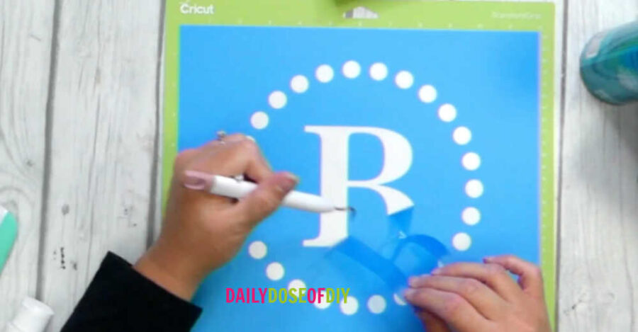 weeding the stencil film to paint a monogram made with Cricut 