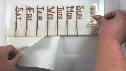 Remove the backing from the transfer paper to apply the weekly menu to the glass