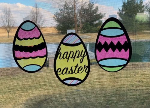 Three Easter Egg Suncatchers hanging in a window made with a Cricut cutting machine