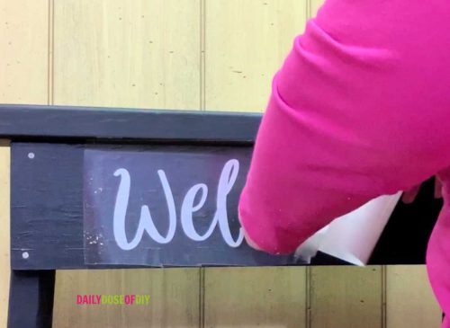 Applying a vinyl welcom decal to DIY hanging plant stand