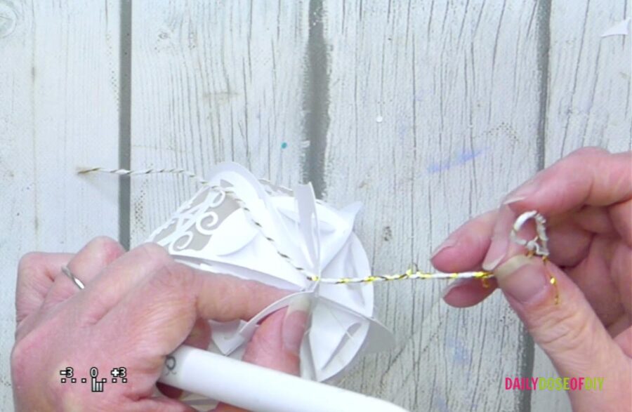 adding string to the top of the white paper christmas ornament 