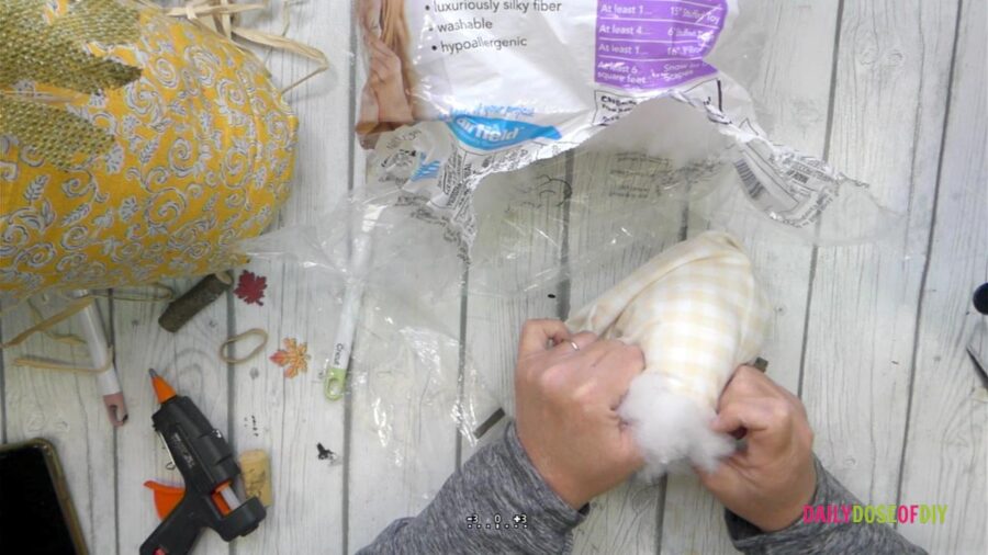Adding stuffing to the fabric pumpkin 