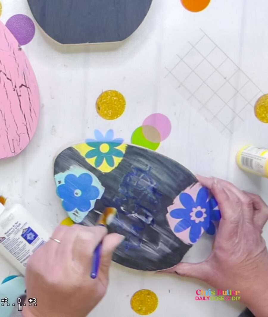 applying elmers glue to make crackle paint on a wooden eggs with flower stencils 