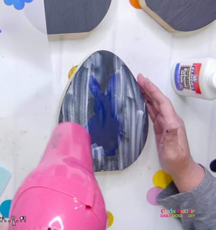 drying the glue on a wooden egg with a hot pink hair dryer 