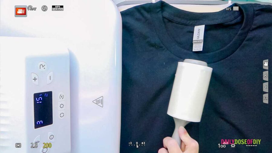 using a lint roller on a black shirt to remove debris before adding white Heat transfer vinyl 